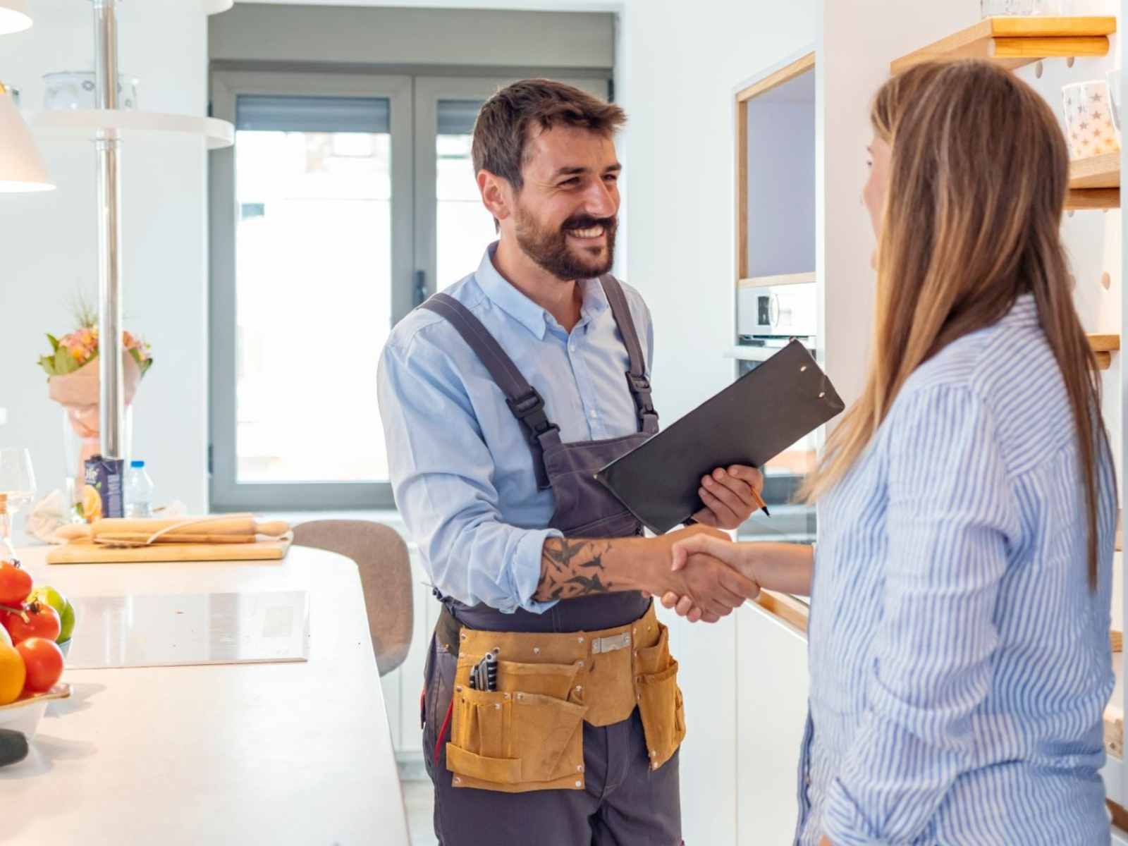 Handyman and client shake hands in kitchen