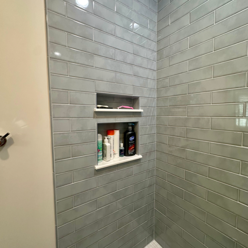 Shower niche with toiletries on gray tiles