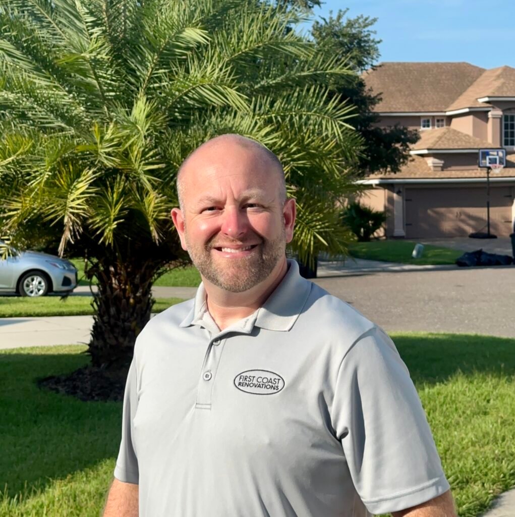 Joe Spak - Owner, smiling outdoors near palm tree and house.